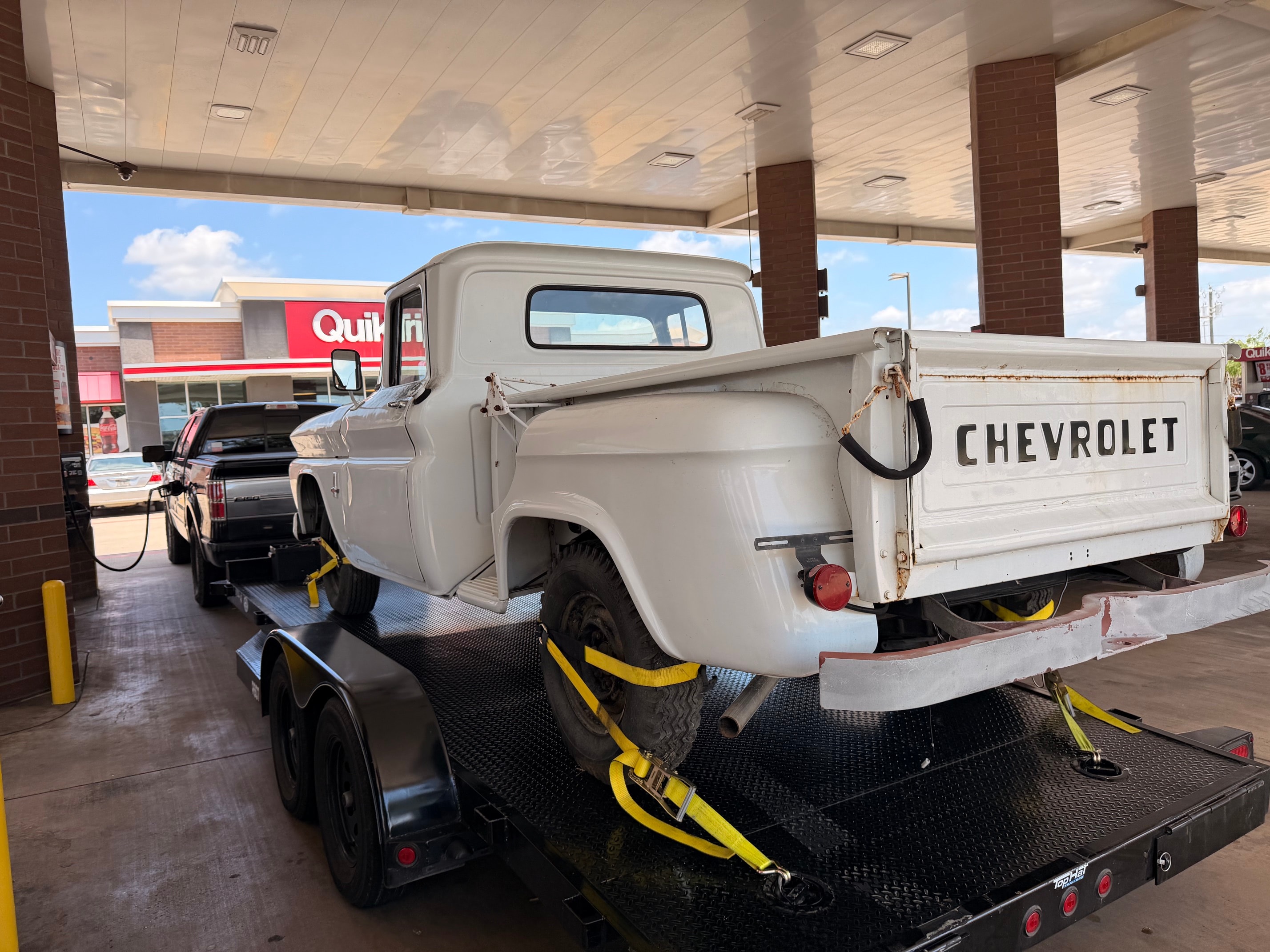 Vintage white Chevrolet truck on car hauler at gas station